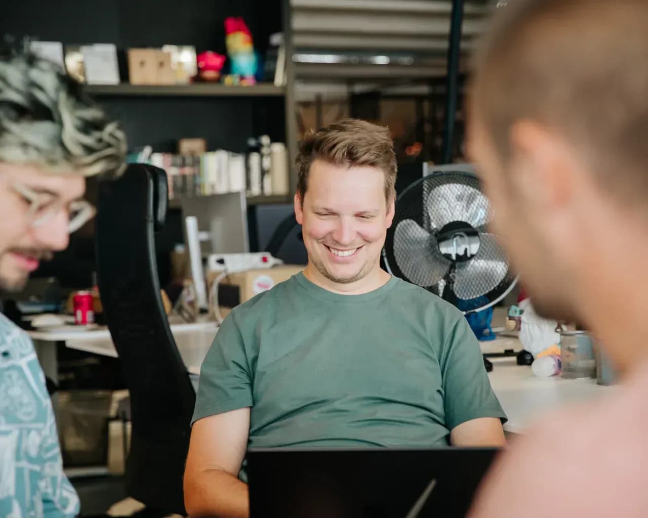 Person sitting and laughing with colleagues in an office environment